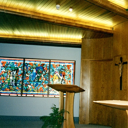 Interior of Chapel with lectern and cross in foreground and stained glass window in background