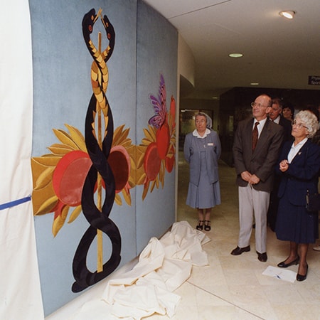 Artwork unveiled on wall as crowd looks on at the opening of the Murdoch Medical Clinic