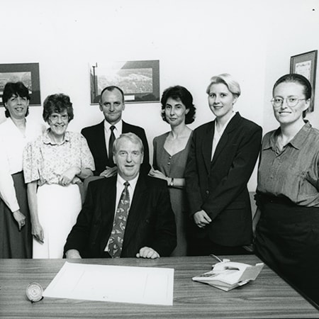 Black and white photograph of the St John of God Murdoch Hospital project team members behind a desk