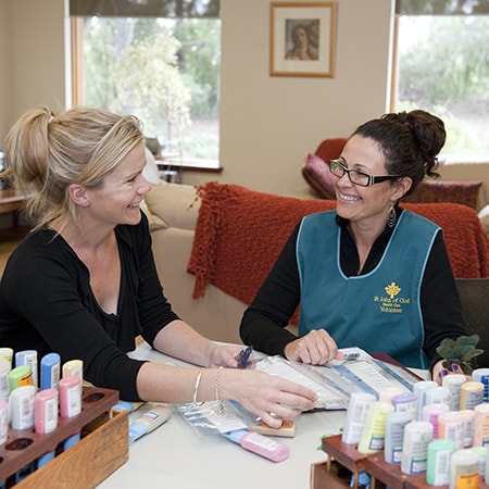 Volunteer and woman talking and smiling while seated at table in the Murdoch Community Hospice